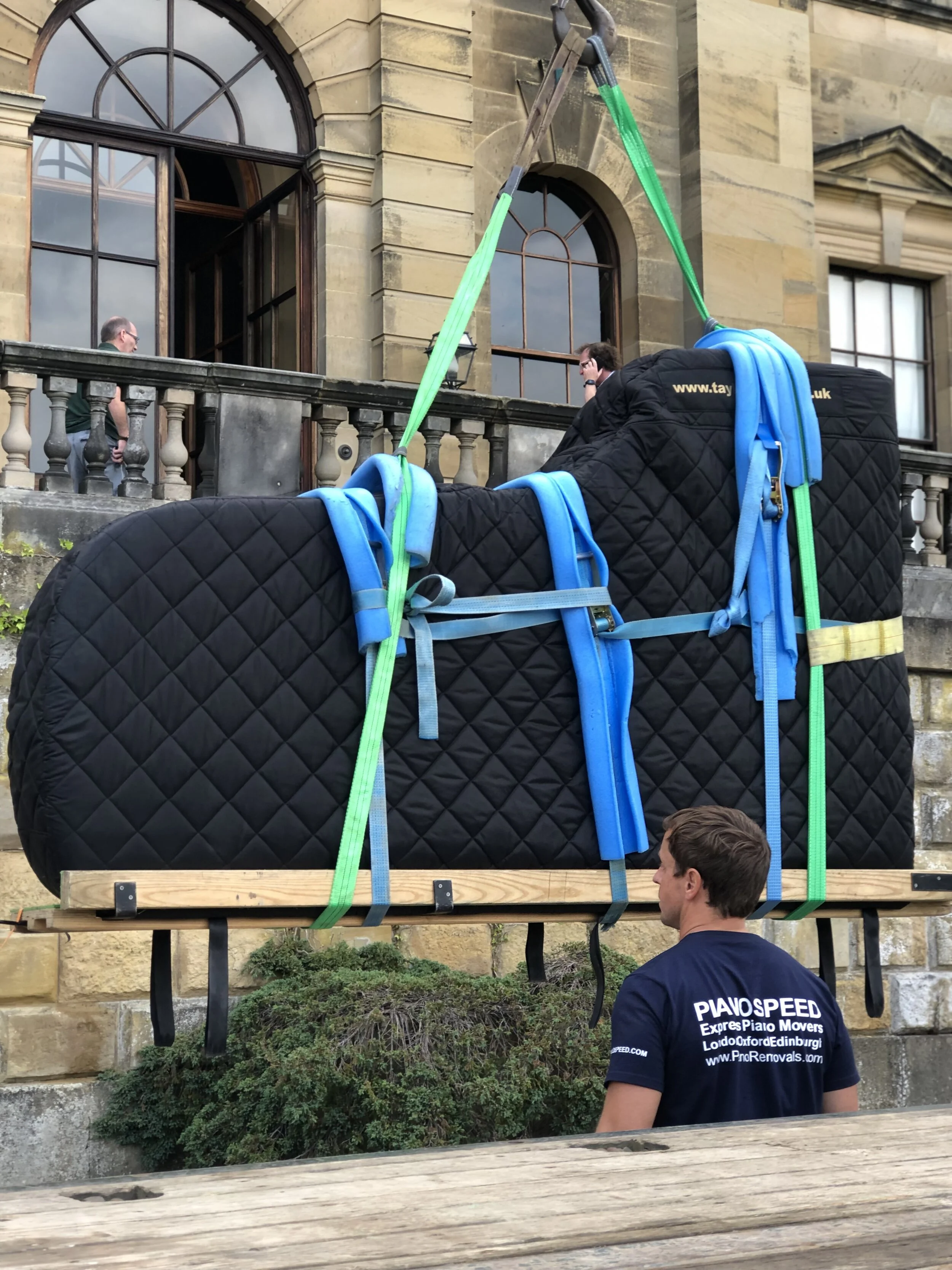 Concert grand piano lifted on straps