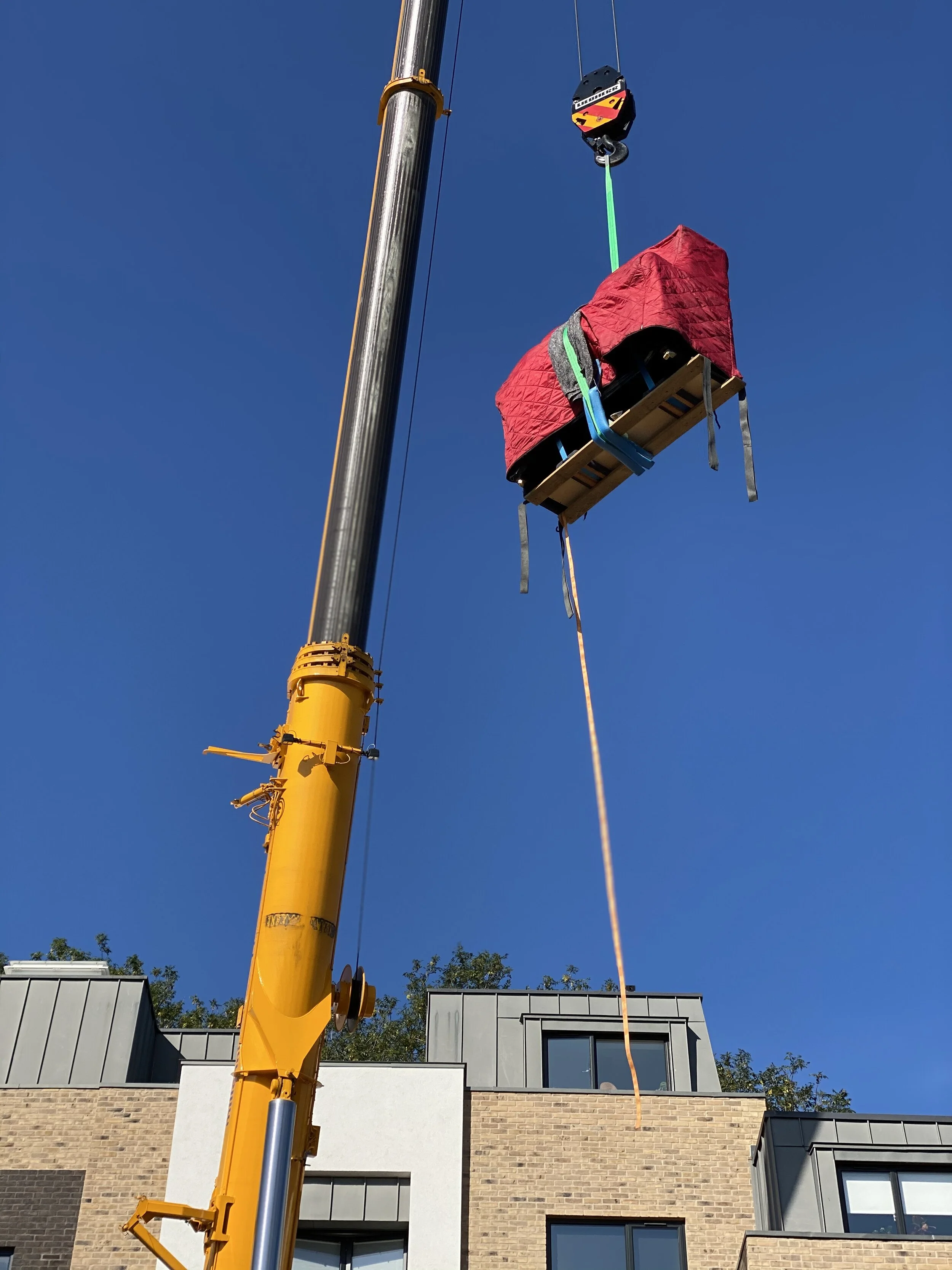 Piano in a quilted transit cover lifted by crane